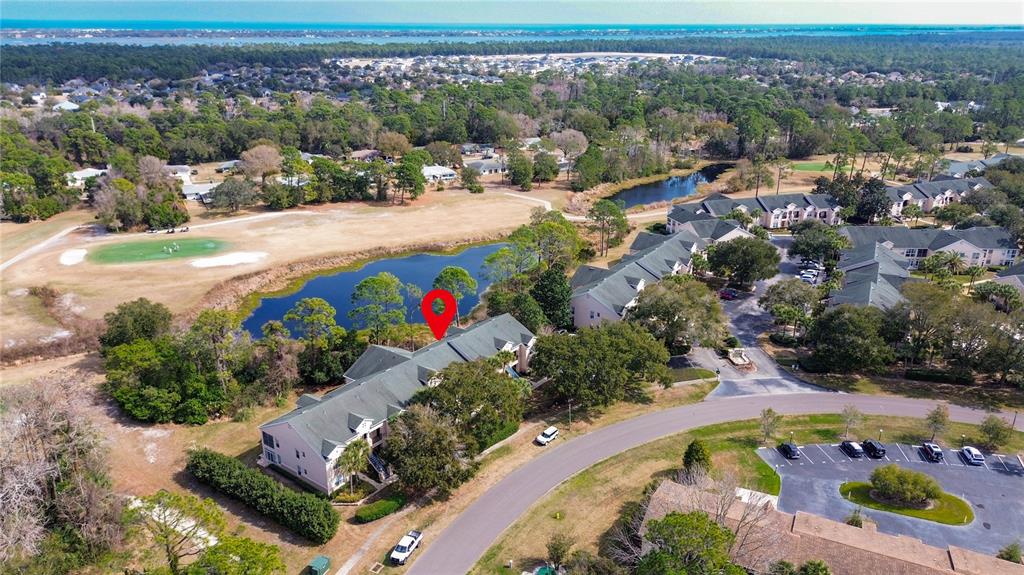 An aerial view shows a multi-unit residential building situated next to a pond and golf course — 705 AUGUSTA CIRCLE UNIT 705, ST AUGUSTINE, FL