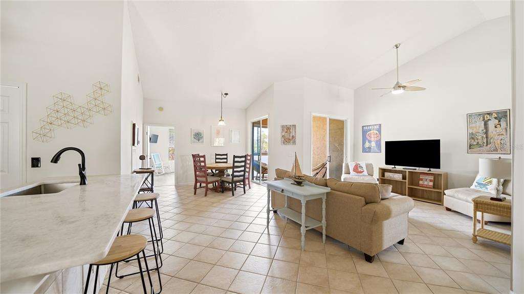 An open-concept living and dining area features tile flooring, vaulted ceilings, and a kitchen island — 705 AUGUSTA CIRCLE UNIT 705, ST AUGUSTINE, FL