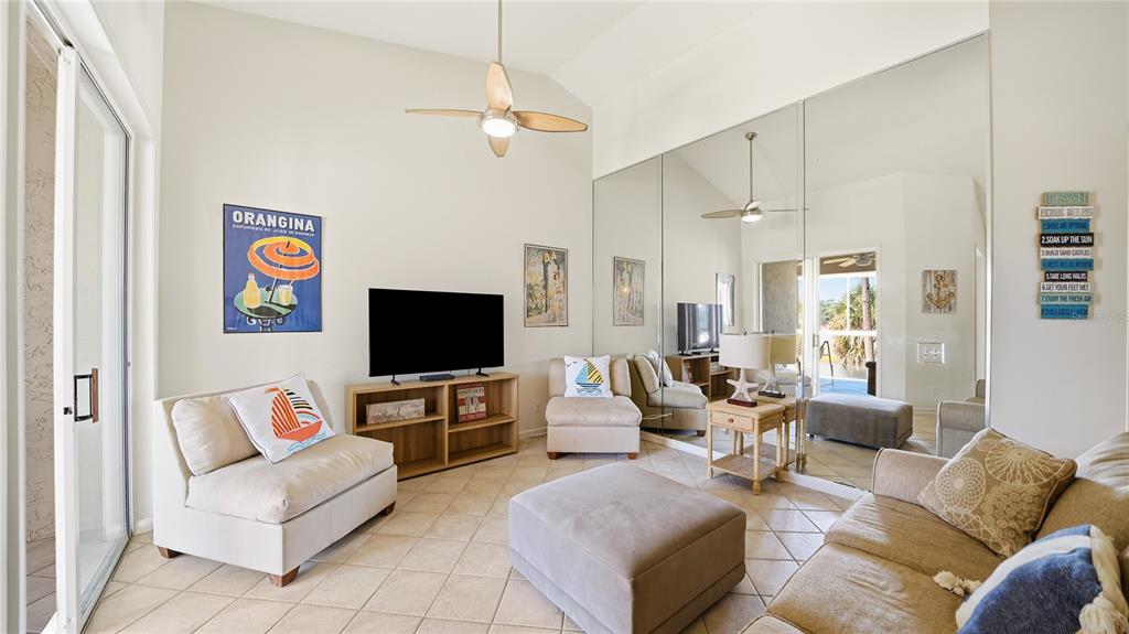 A living room features tile floors, a vaulted ceiling, mirrored walls, and a television console — 705 AUGUSTA CIRCLE UNIT 705, ST AUGUSTINE, FL