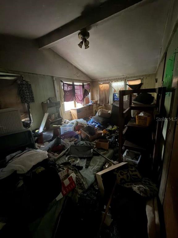 A cluttered, dimly lit room with wood-paneled walls, a sloped ceiling, and a ceiling fan — 410 N ORANGE AVE, UMATILLA, FL