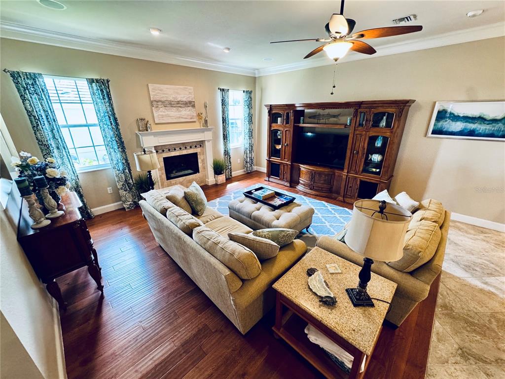 A living room features hardwood floors, a fireplace, a large entertainment center, and beige sofas — 1024 SAN MATEO DRIVE, PUNTA GORDA, FL
