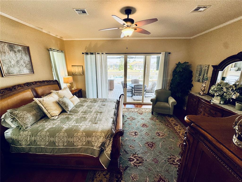 A bedroom features a wooden bed, a patterned area rug, and sliding glass doors to a patio — 1024 SAN MATEO DRIVE, PUNTA GORDA, FL