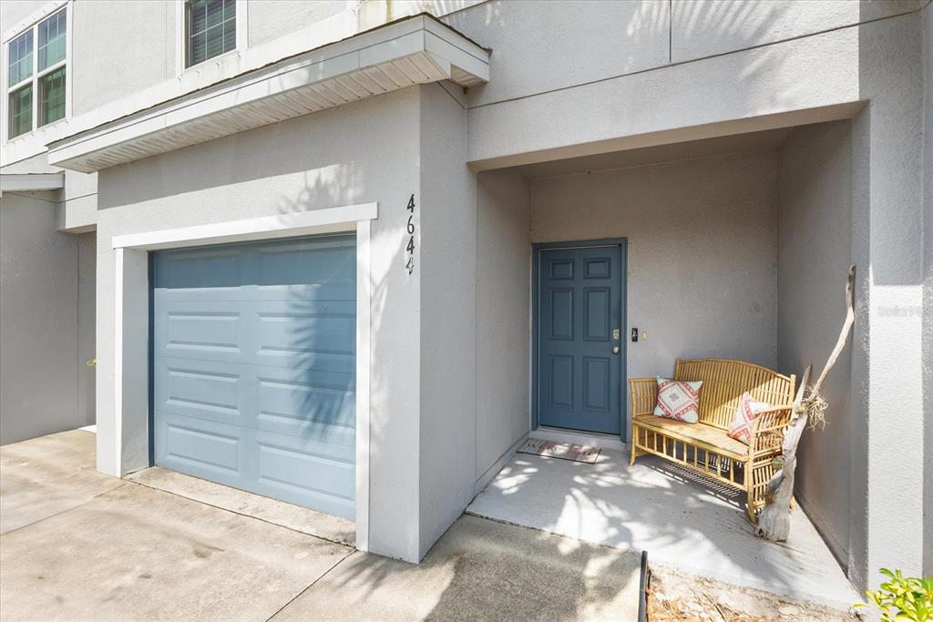 The exterior of a house features a blue garage door, a front door, and a bench — 4644 VIGNETTE WAY, SARASOTA, FL