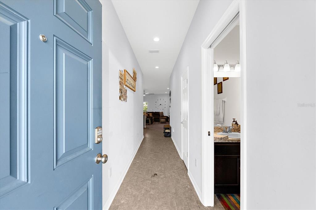 A view from an open blue front door looking down a hallway toward a living area — 4644 VIGNETTE WAY, SARASOTA, FL