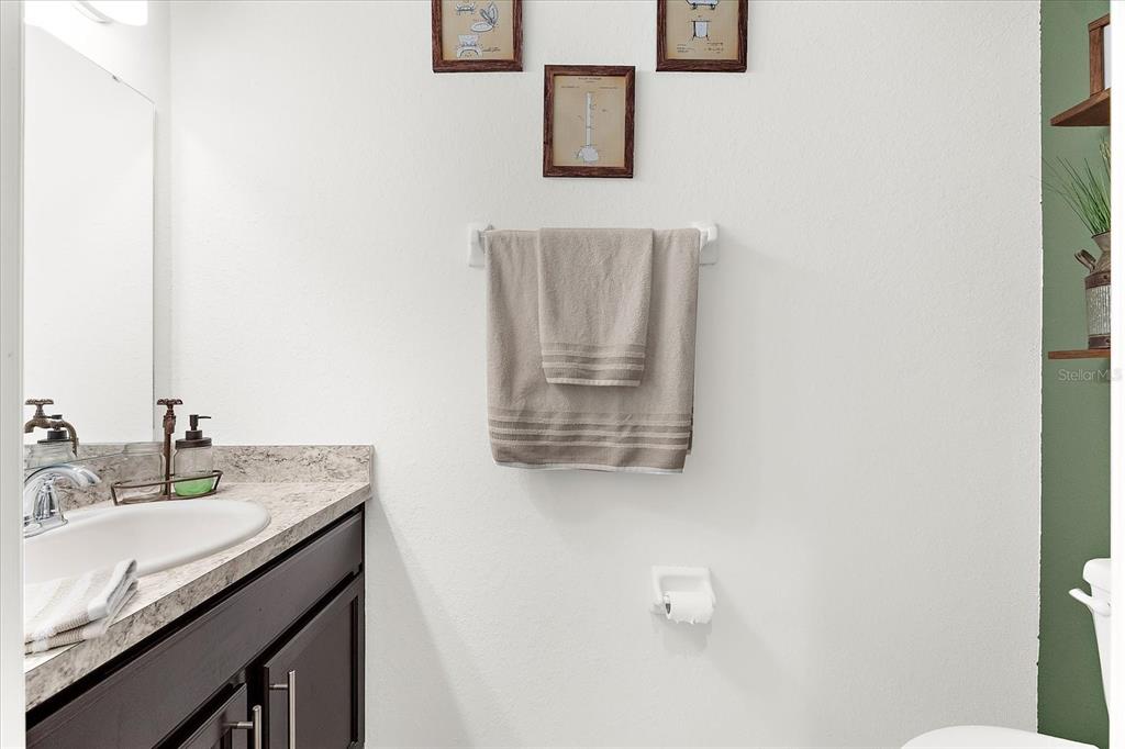 A bathroom features a dark vanity with a stone countertop, a towel rack, and wall art — 4644 VIGNETTE WAY, SARASOTA, FL