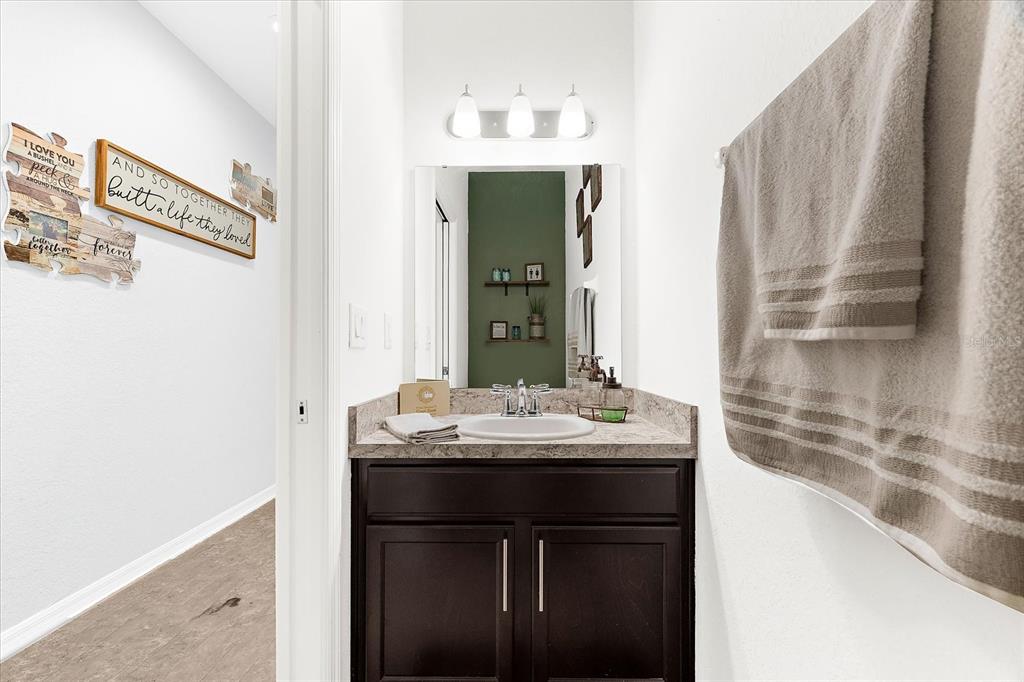 A bathroom features a dark wood vanity, a stone countertop, and a green accent wall — 4644 VIGNETTE WAY, SARASOTA, FL