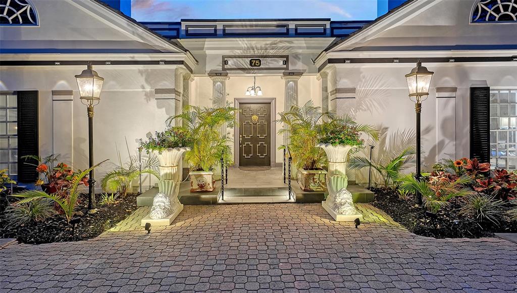 The exterior entrance of a house features a paved walkway, two large planters, and lamps — 75 OSPREY POINT DRIVE, OSPREY, FL
