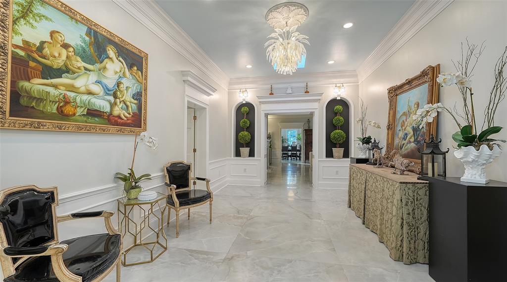 A formal foyer features marble floors, a crystal chandelier, arched alcoves, and ornate framed paintings — 75 OSPREY POINT DRIVE, OSPREY, FL