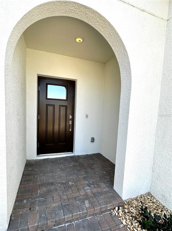 A dark brown front door is set within a white arched entryway with brick pavers — 5309 KELPER HOOK COURT, WIMAUMA, FL