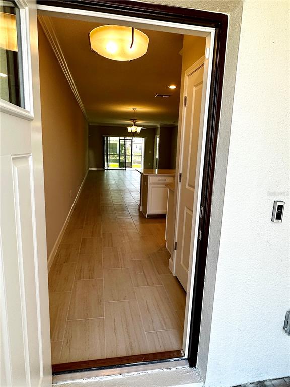 A view through an open doorway into a home with tile flooring and kitchen cabinetry — 5309 KELPER HOOK COURT, WIMAUMA, FL