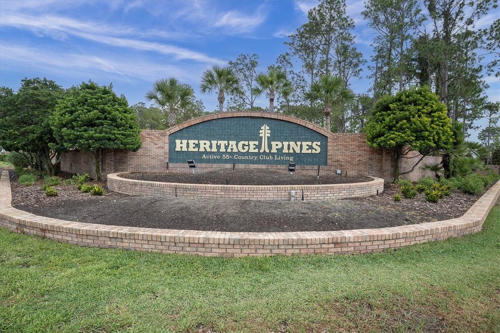 A brick entrance sign for Heritage Pines sits behind a tiered brick planter bed — 11250 HOLLANDER AVENUE, HUDSON, FL