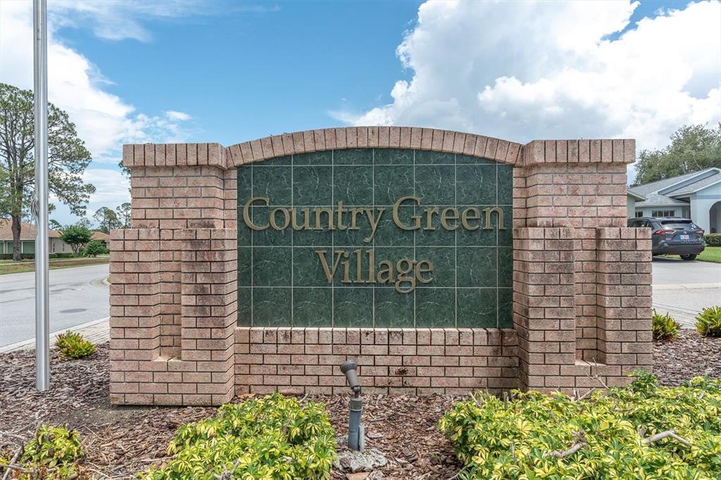 A brick monument sign for Country Green Village stands outdoors under a blue sky — 11250 HOLLANDER AVENUE, HUDSON, FL