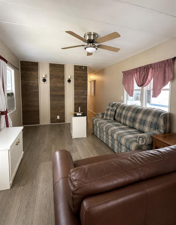 A living room features wood-paneled accent walls, a plaid sofa, and light wood-look flooring — 15423 SANTA FE TRL, EUSTIS, FL