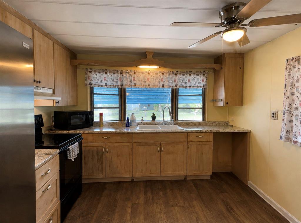 A kitchen with light wood cabinets, a black stove, a stainless refrigerator, and a window — 15423 SANTA FE TRL, EUSTIS, FL