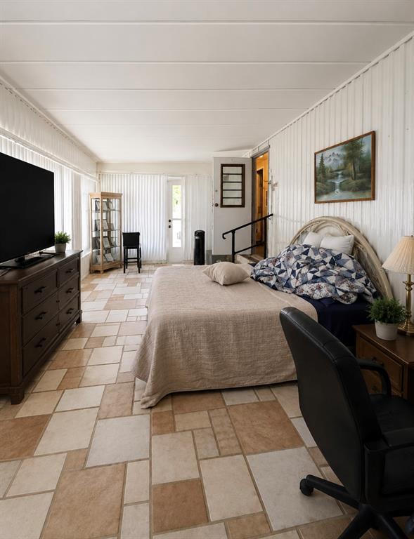 A bedroom with tile flooring, a large bed, a television on a dresser, and a desk — 15423 SANTA FE TRL, EUSTIS, FL