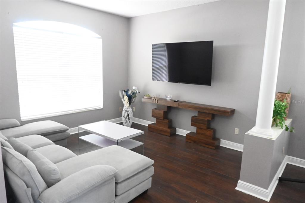 A living room features a gray sectional sofa, a white coffee table, and a wall-mounted television — 919 JAYBEE AVENUE, DAVENPORT, FL