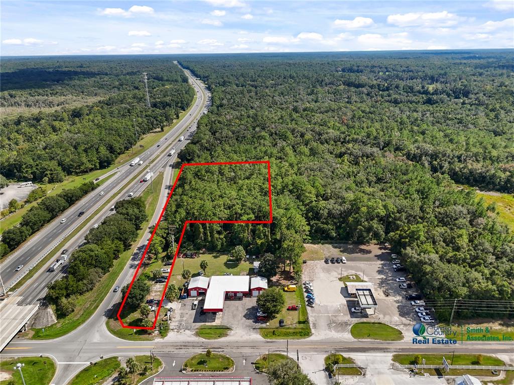 An aerial view shows a wooded lot outlined in red next to a highway — SE CR 234, MICANOPY, FL