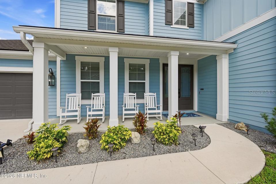 A blue house exterior features a covered front porch with four white rocking chairs — 128 WINDWALKER DRIVE, ST AUGUSTINE, FL