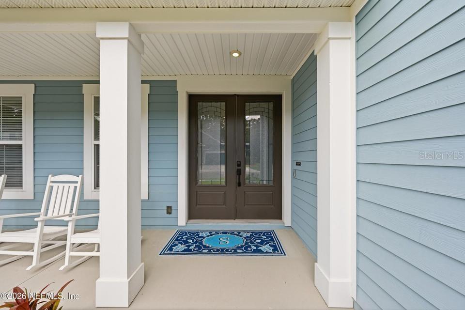 A covered front porch features light blue siding, white columns, and a double front door — 128 WINDWALKER DRIVE, ST AUGUSTINE, FL