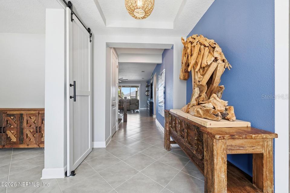 A hallway features a blue accent wall, a wooden console table, and a sliding barn door — 128 WINDWALKER DRIVE, ST AUGUSTINE, FL