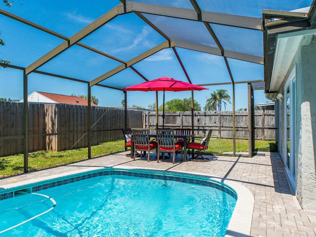 A swimming pool with a patio dining set under a screened-in enclosure in a backyard — 3645 OVERLAND, HOLIDAY, FL