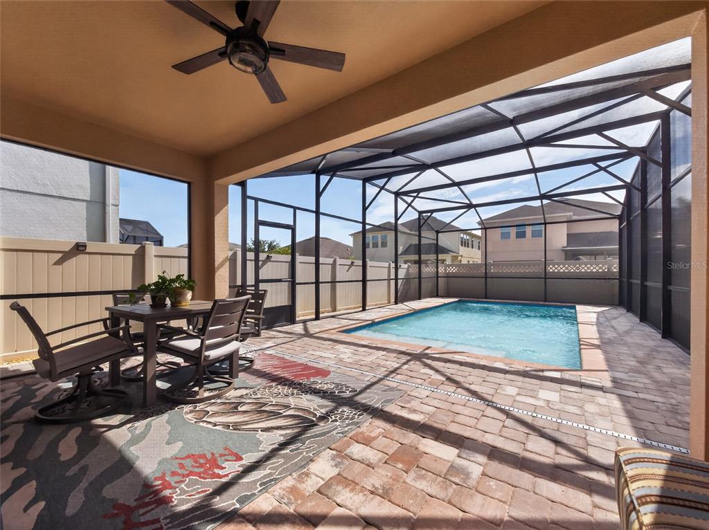 A covered patio features a dining set, a ceiling fan, and a screened-in swimming pool — 9043 HORIZON POINTE TRAIL, WINDERMERE, FL
