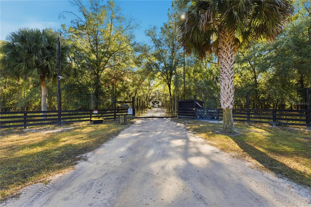 A dirt driveway leads to a gated entrance with a sign reading Circle S Ranch — TBD (Lot 1) NE 115TH LANE ROAD, FORT MC COY, FL