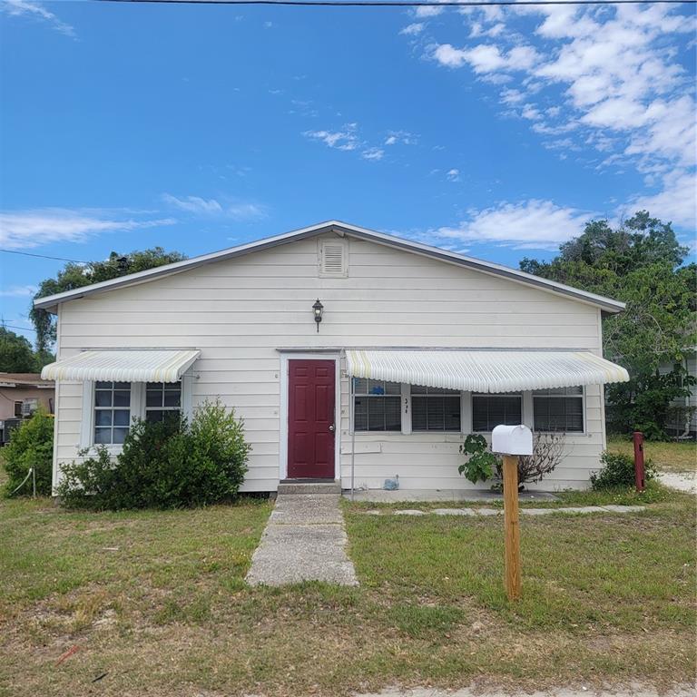 A single-story house with white horizontal siding, a red front door, and striped window awnings — 314 WALNUT STREET, AUBURNDALE, FL