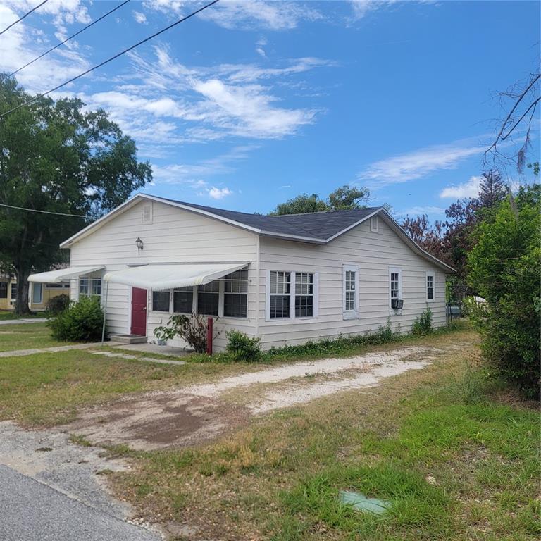 A single-story house with white siding, a red front door, and a gravel driveway — 314 WALNUT STREET, AUBURNDALE, FL