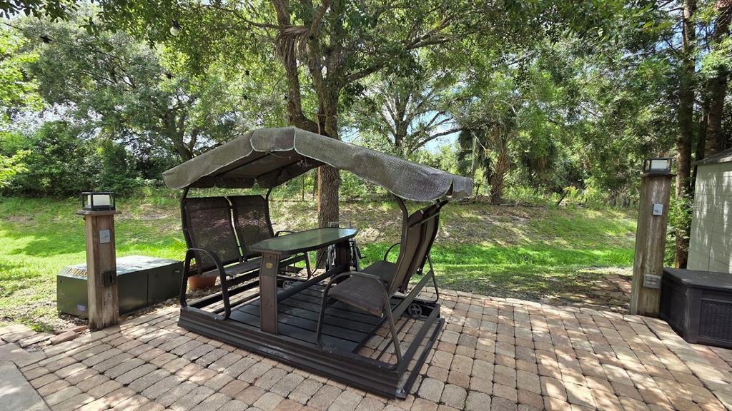 A patio features a covered swing set with a built-in table on a paved surface — 171 APPALOOSA TRAIL, RIVER RANCH, FL