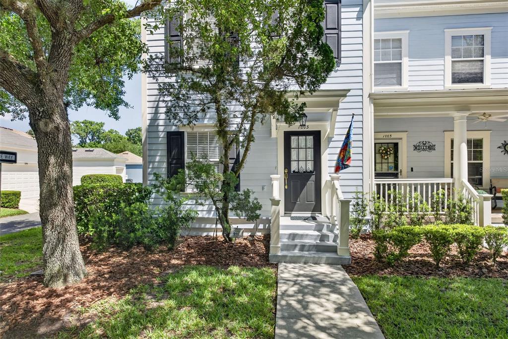 A light blue two-story townhouse with a dark front door and a small front porch — 1003 OLD BLUSH ROAD, CELEBRATION, FL