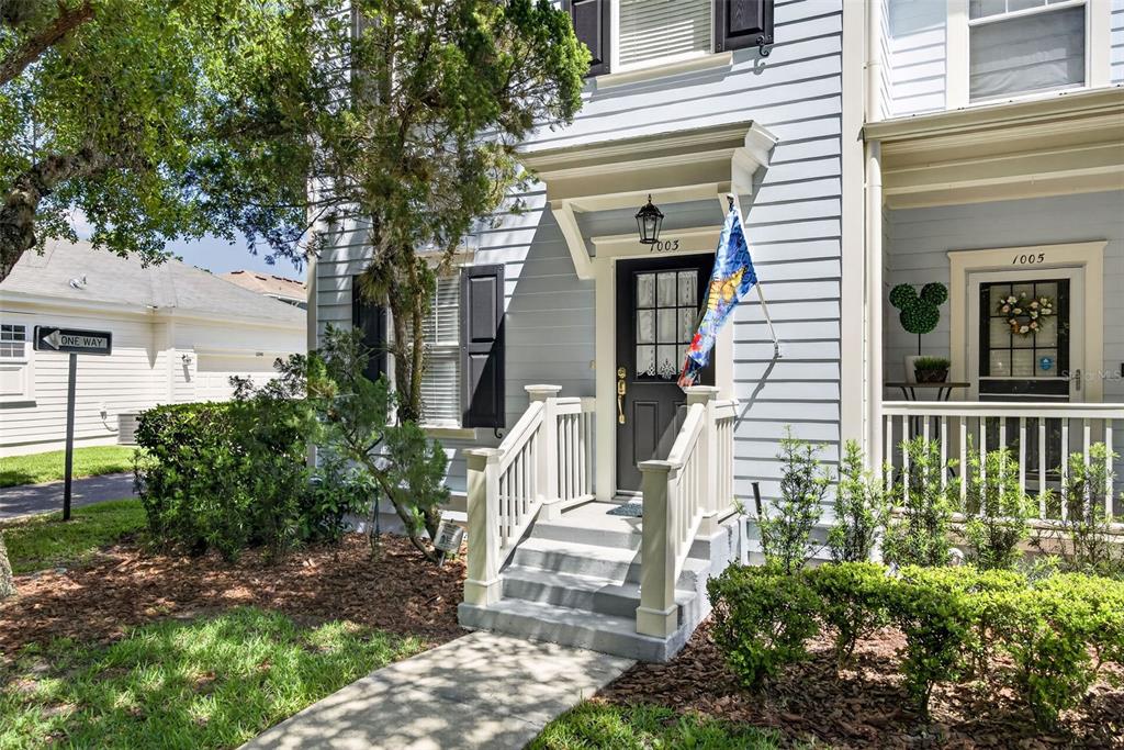 A light blue townhouse exterior features a front porch with stairs and a dark door — 1003 OLD BLUSH ROAD, CELEBRATION, FL