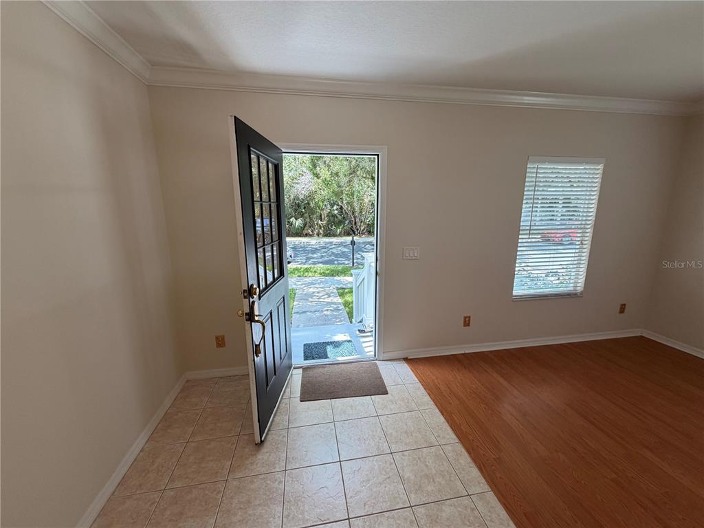 An entryway with tile flooring opens to a living area with wood-look floors and blinds — 1003 OLD BLUSH ROAD, CELEBRATION, FL