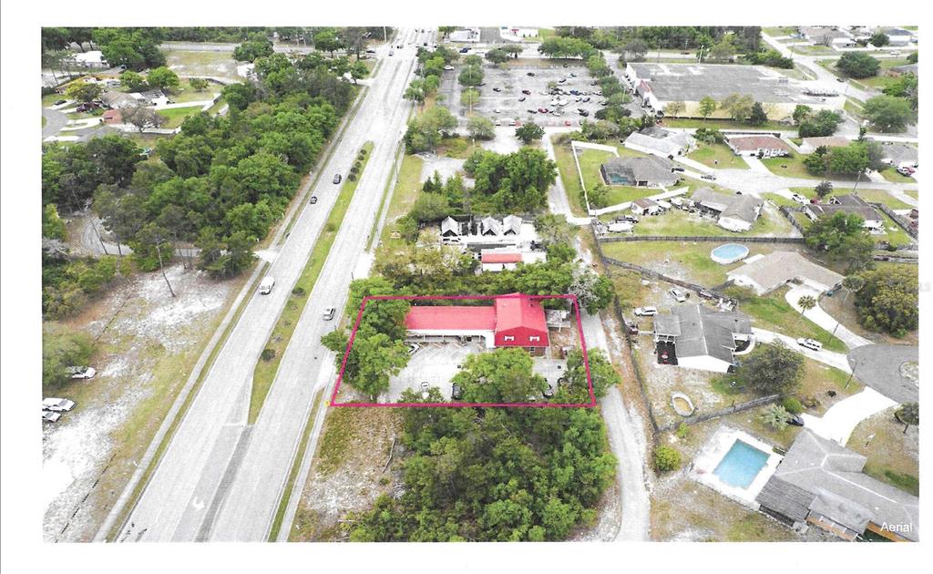 An aerial view shows a commercial building with a red roof outlined in pink — 2820 HOWLAND BOULEVARD, DELTONA, FL