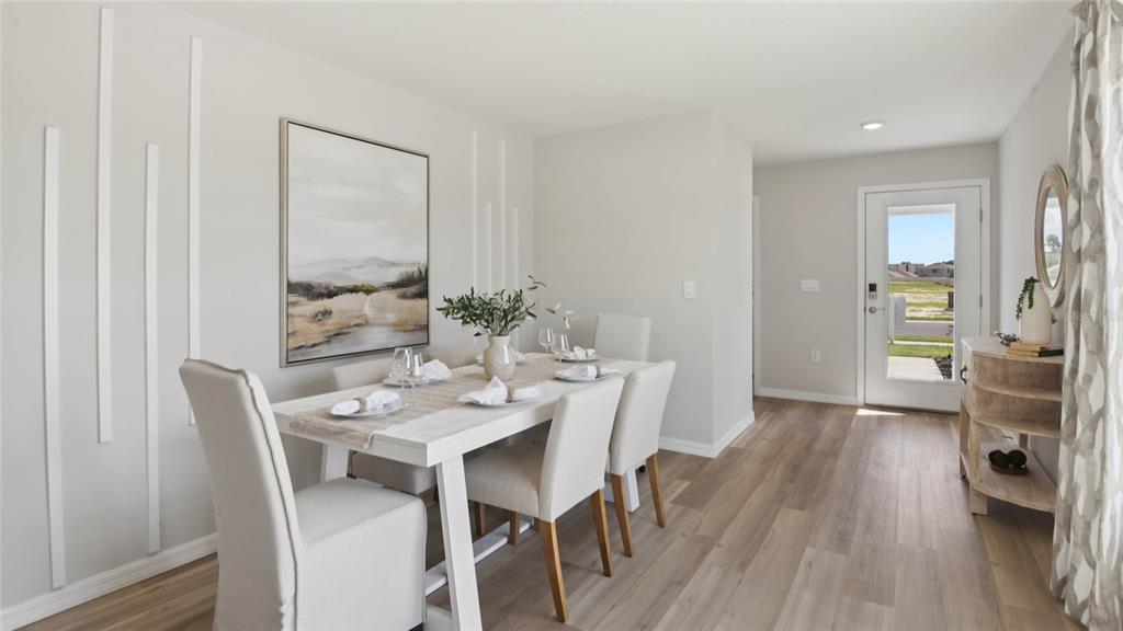 A dining room features a white table, upholstered chairs, wall molding, and light wood flooring — 24333 NW 10TH ROAD, NEWBERRY, FL