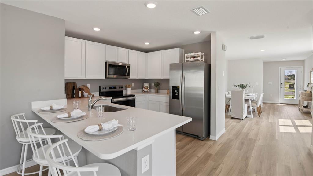 A modern kitchen features white cabinets, stainless steel appliances, and a central island with seating — 24333 NW 10TH ROAD, NEWBERRY, FL