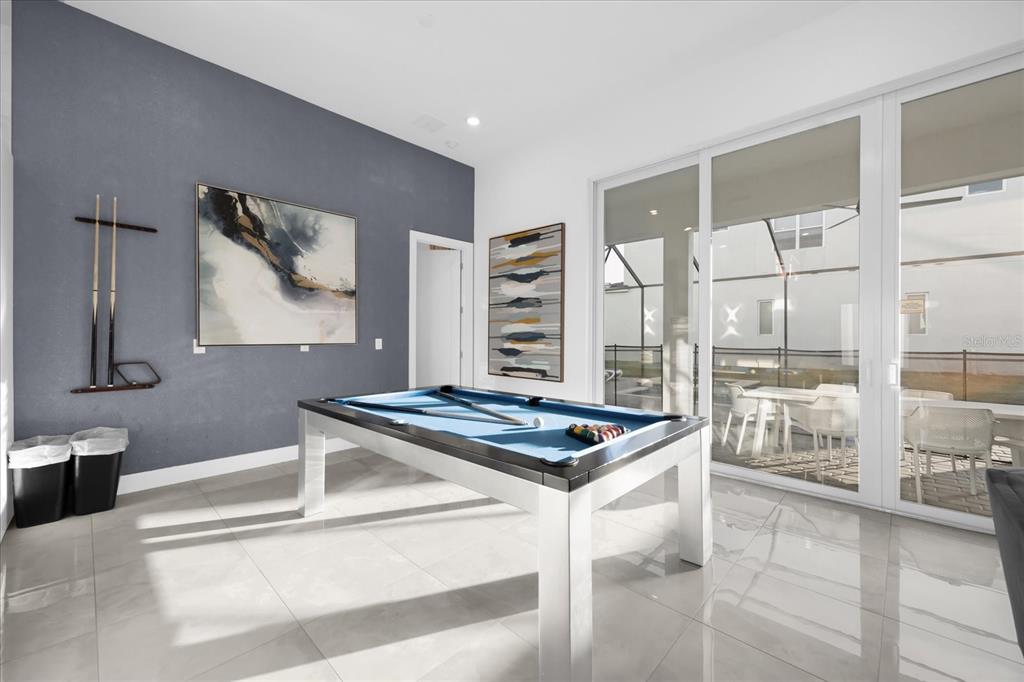 A game room features a pool table, blue accent wall, and sliding glass doors to a patio — 2137 PINE OAK LOOP, DAVENPORT, FL