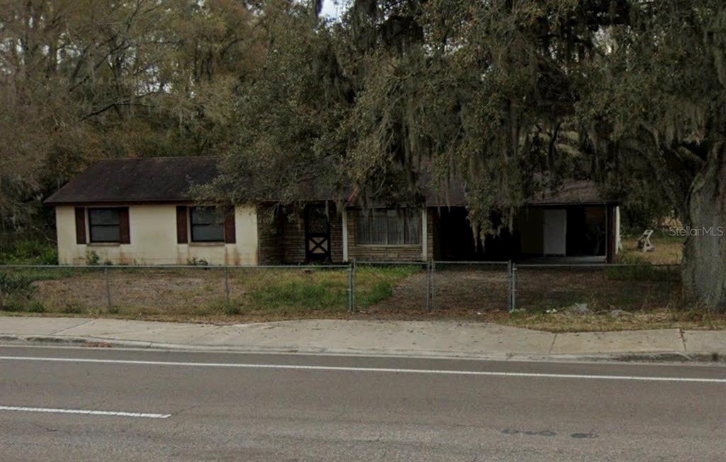 A single-story house with a beige exterior, brown shutters, and a carport under large trees — 330 MARCUM ROAD, LAKELAND, FL