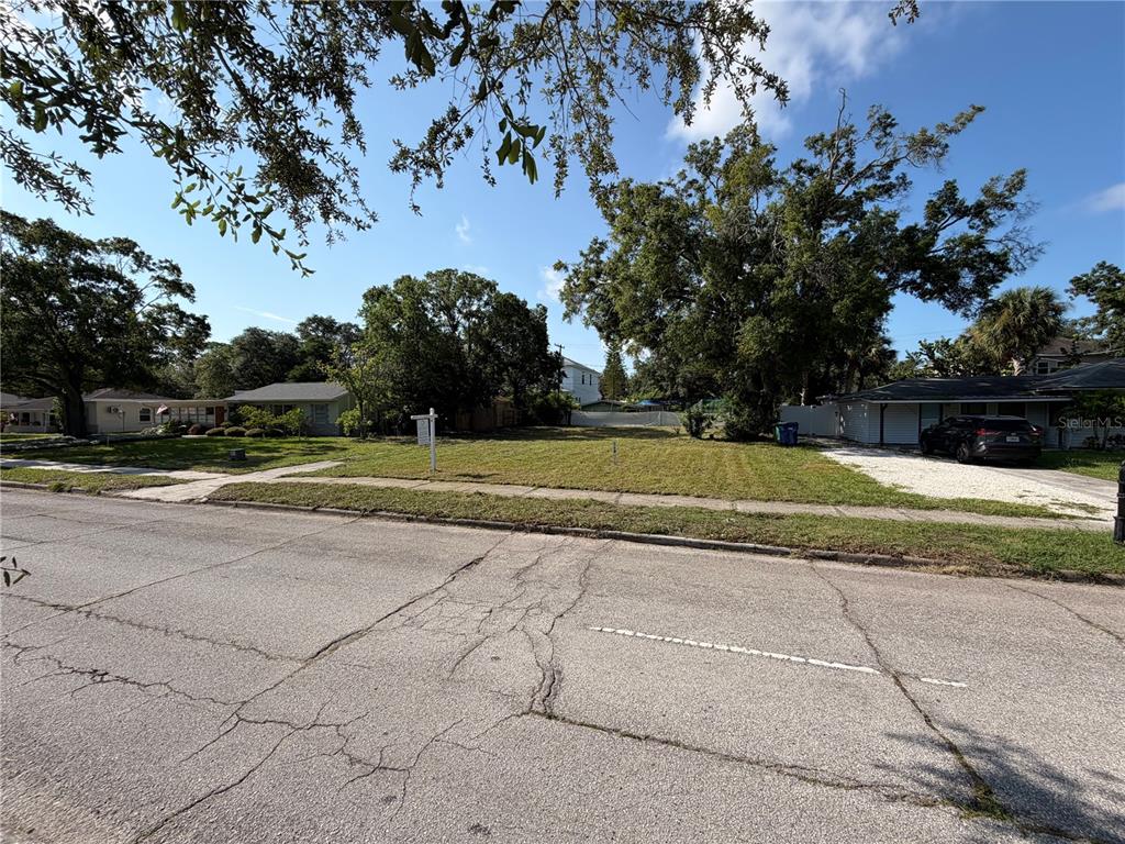 A vacant, grassy residential lot sits between two houses on a paved street — 4608 W EL PRADO BOULEVARD, TAMPA, FL