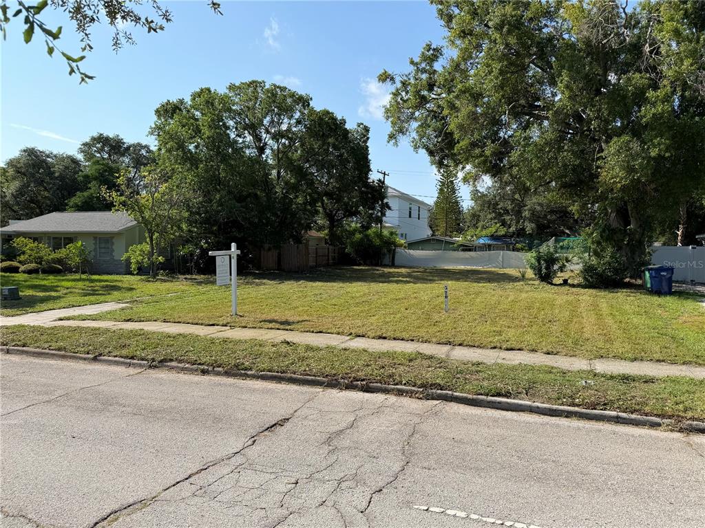 A vacant, grassy residential lot sits between two houses along a paved street — 4608 W EL PRADO BOULEVARD, TAMPA, FL