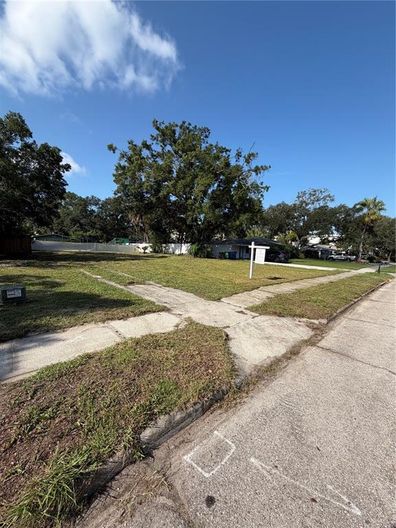 A vacant residential lot features a grassy surface, a sidewalk, and a real estate sign — 4608 W EL PRADO BOULEVARD, TAMPA, FL