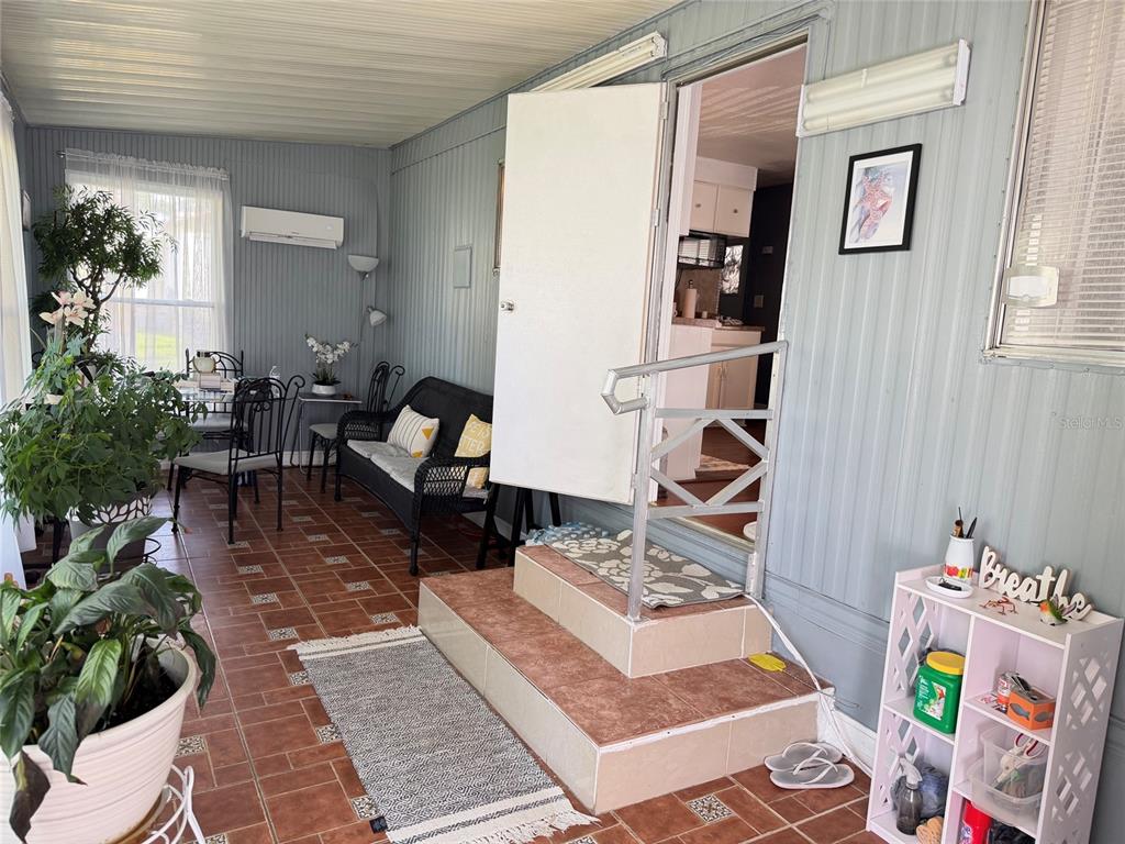 A sunroom with tiled floors, a seating area, and steps leading into the home's interior — 5578 DENISE AVE, ORLANDO, FL
