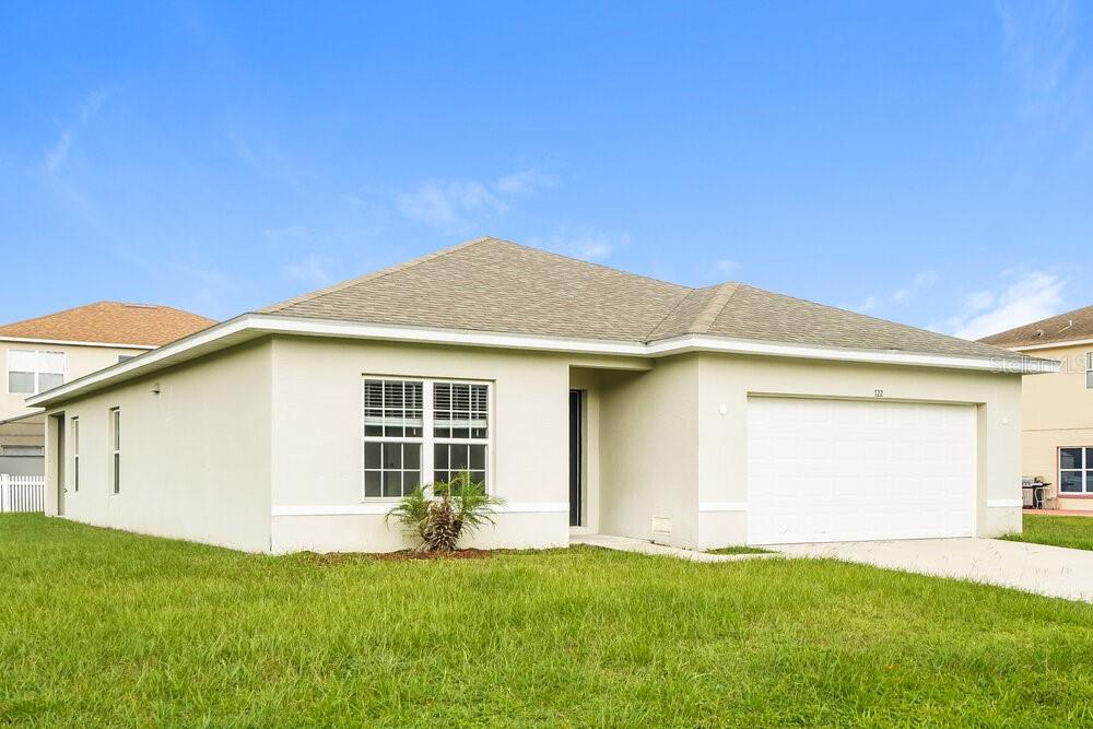 A single-story house with beige stucco siding, a shingled roof, and a two-car garage — 722 FULMAR COURT, POINCIANA, FL