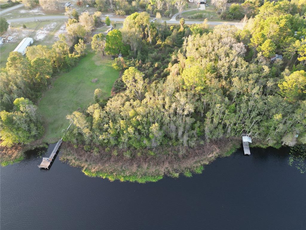 An aerial view shows a grassy yard, dense trees, and two docks on a lake — #8 MITCHEL WAY, EUSTIS, FL