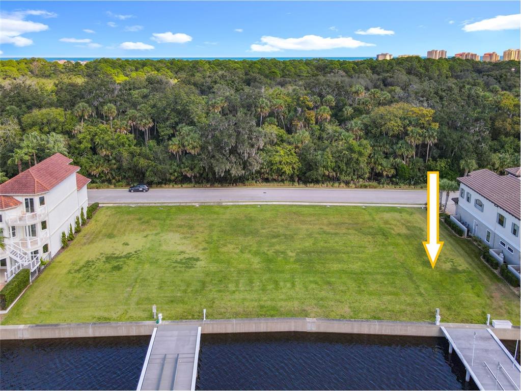 An aerial view shows a vacant waterfront lot situated between two multi-story residential buildings — 210 HARBOR VILLAGE POINT N, PALM COAST, FL