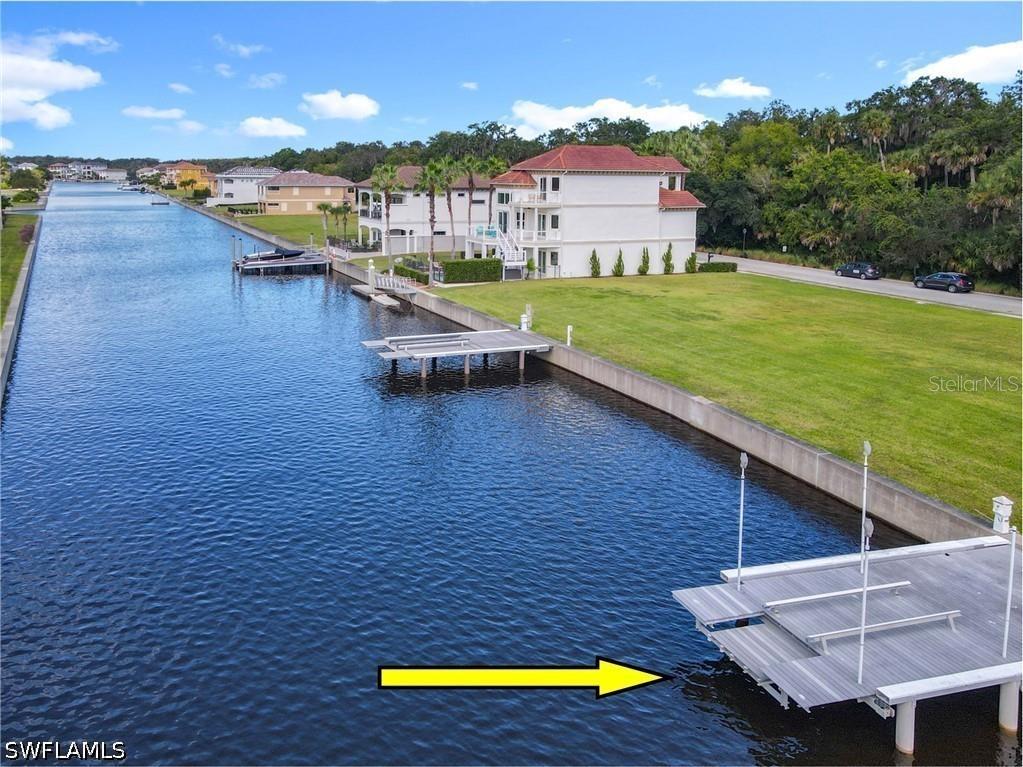 A canal view features a large white house with a dock and a boat lift — 210 HARBOR VILLAGE POINT N, PALM COAST, FL