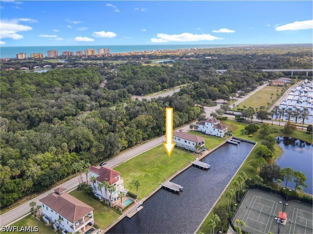 An aerial view shows a vacant waterfront lot situated between two houses and a canal — 210 HARBOR VILLAGE POINT N, PALM COAST, FL