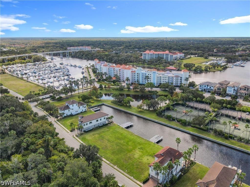 An aerial view shows a waterfront residential area with a marina, canal, and tennis courts — 210 HARBOR VILLAGE POINT N, PALM COAST, FL