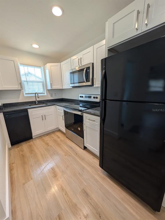 A kitchen and living area with light wood-look flooring, white cabinets, and a ceiling fan — 1834 28TH AVENUE N, ST PETERSBURG, FL