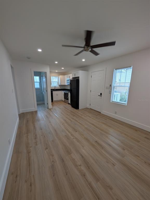 An empty room features light wood-look flooring, white walls, a ceiling fan, and a mini-split — 1834 28TH AVENUE N, ST PETERSBURG, FL